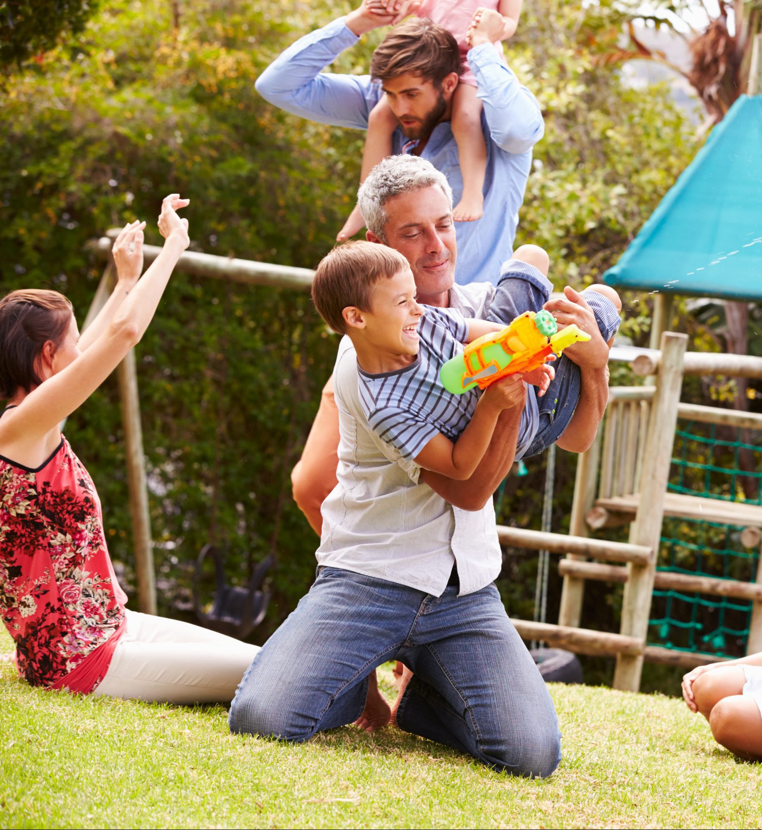 Adults and kids having fun with water pistols in a garden